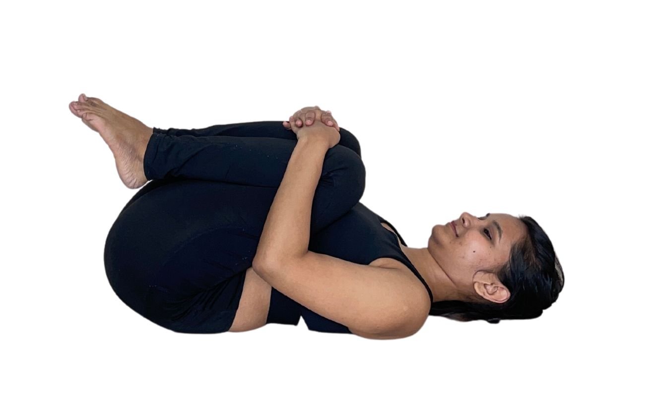 a woman in black yoga clothes doing single leg wind relieving pose