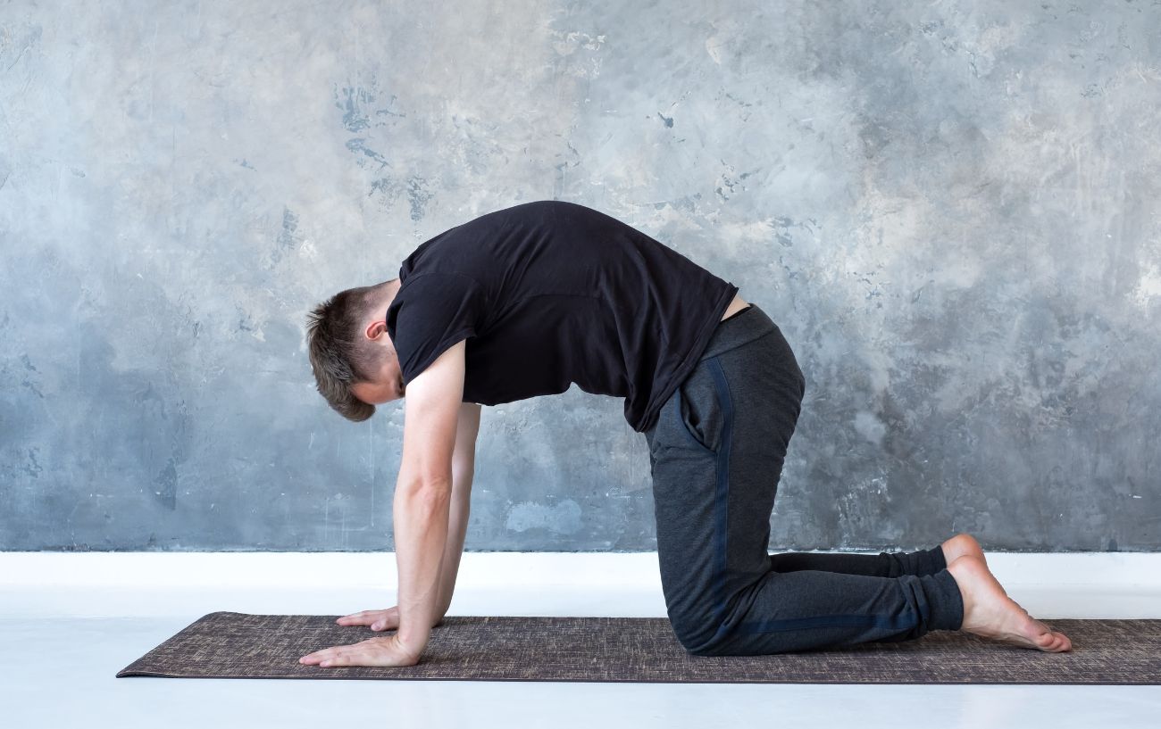 a man doing yoga for neck and shoulders cat pose