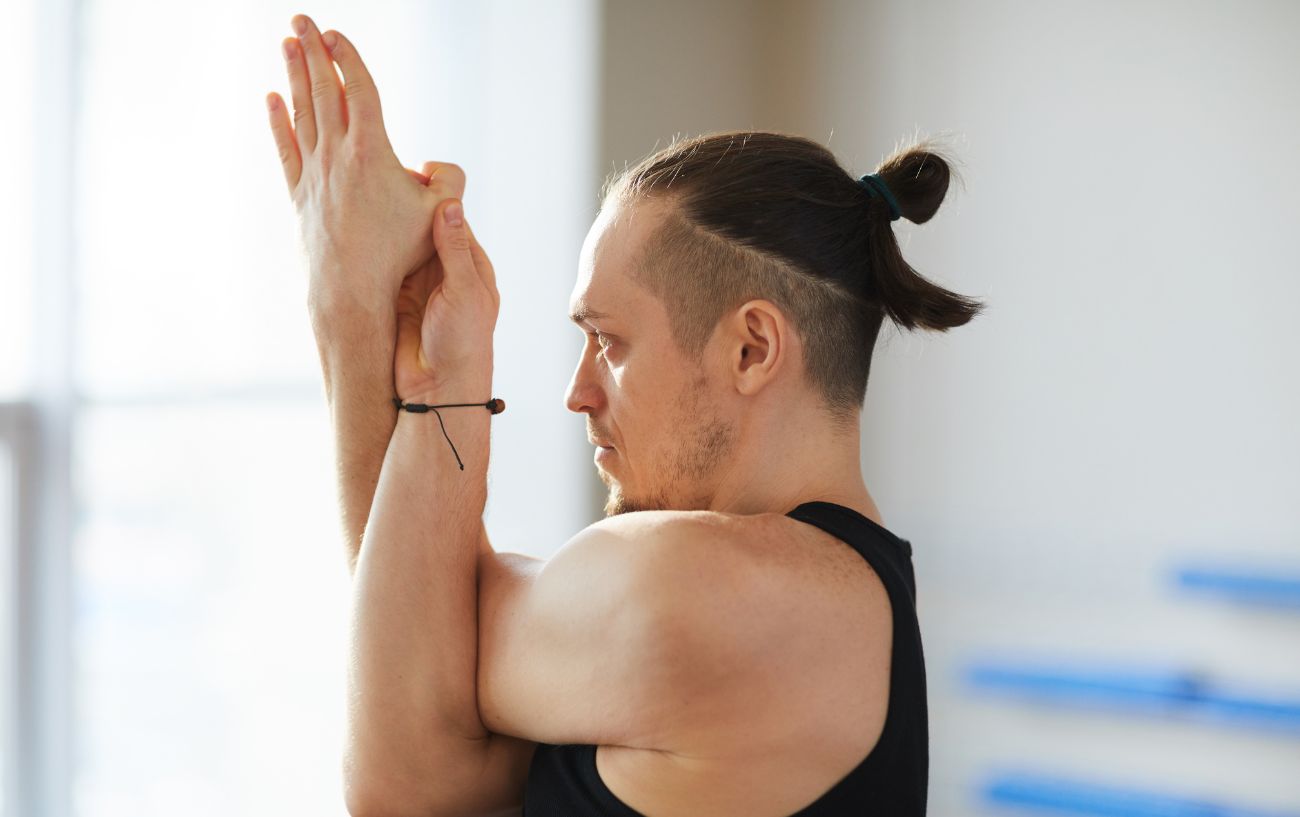 a man doing eagle arms a yoga for neck and shoulders pose