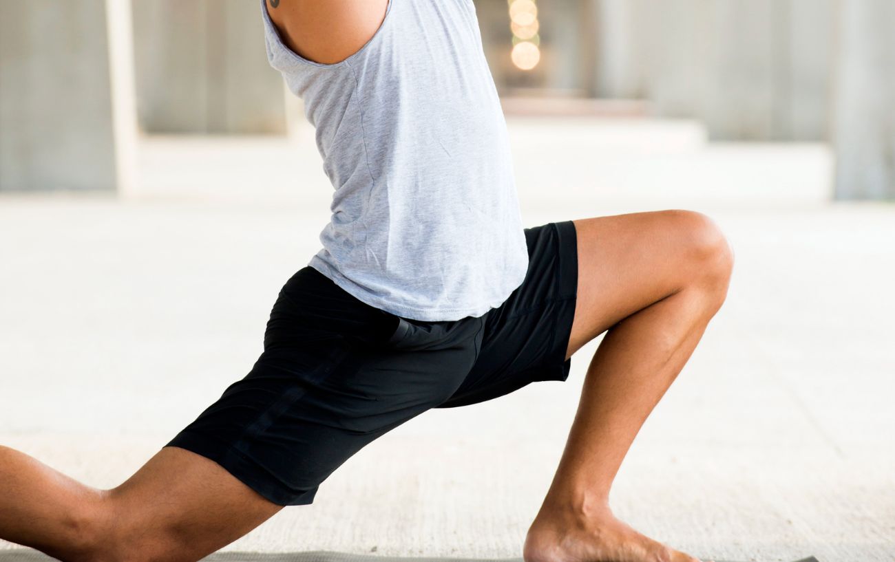 A man lunging in yoga clothes.