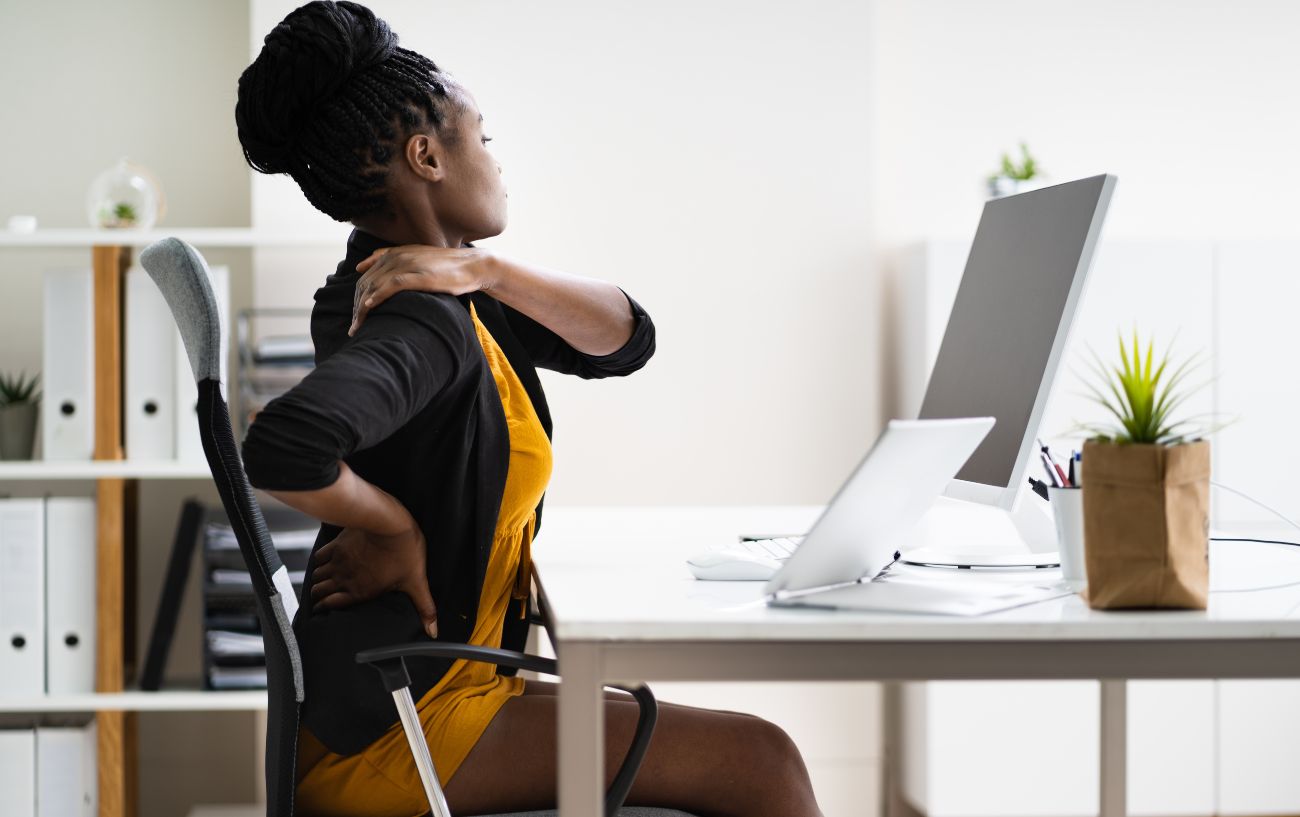 a woman stretching her back at her desk